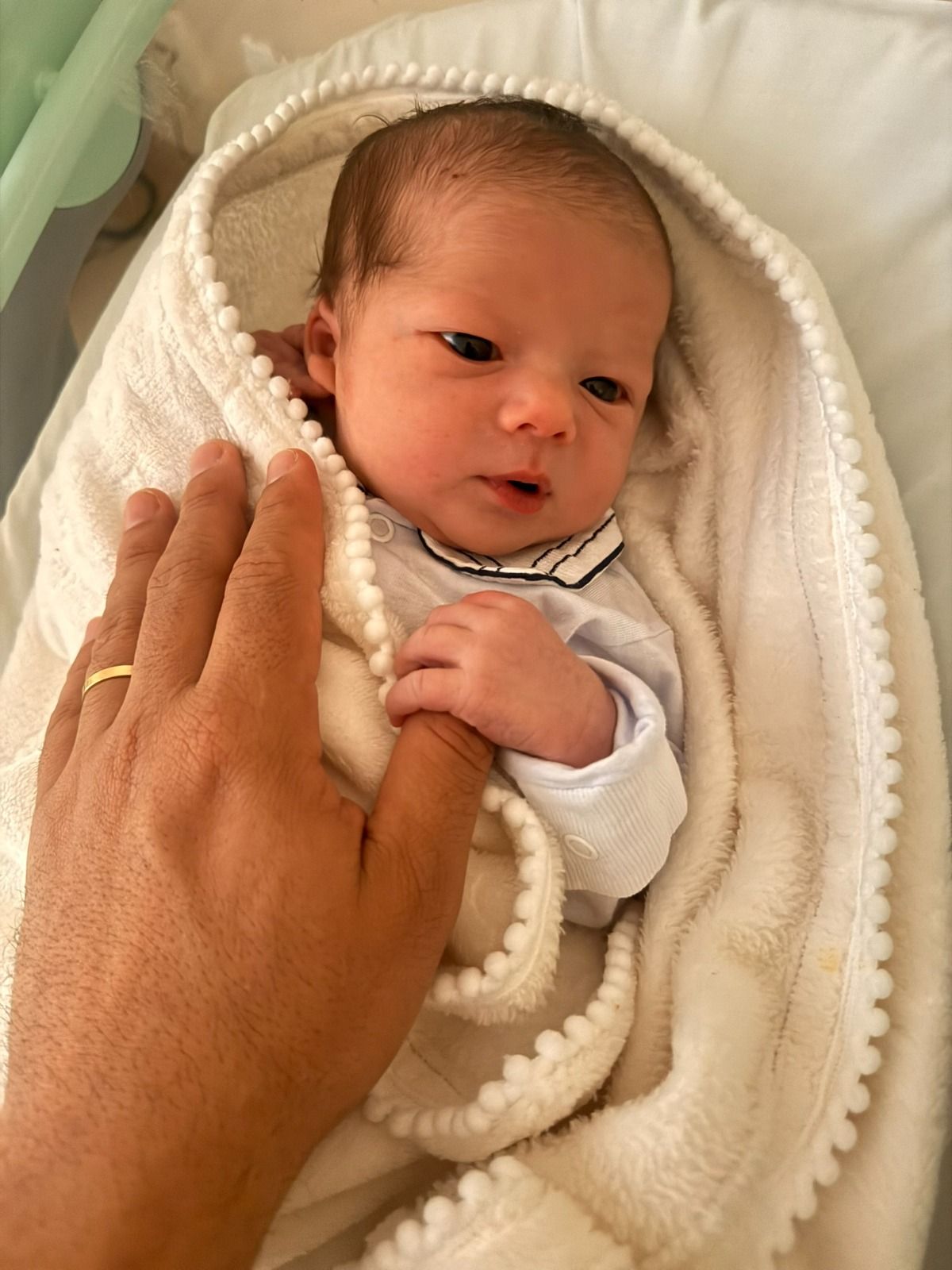 A mão do Benjamin segurando o dedo de um adulto.